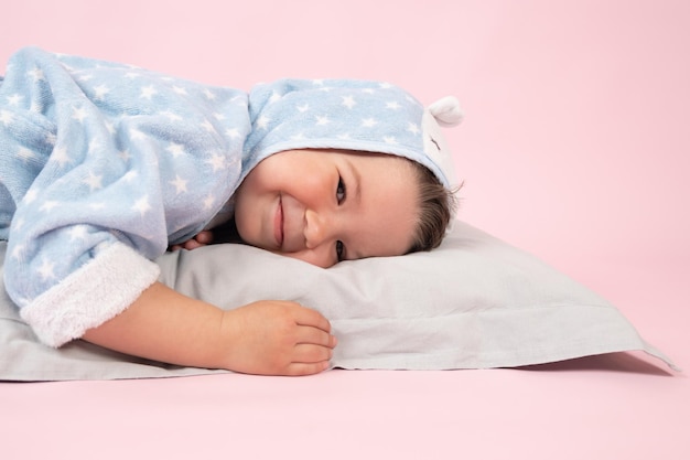 Ragazzo sorridente felice è sdraiato su uno sfondo rosa cuscino Foto di alta qualità