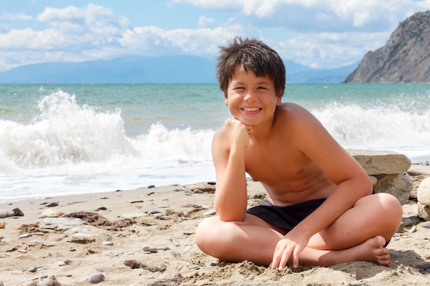 Ragazzo sorridente felice sulla spiaggia del mare