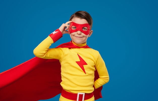 Ragazzo sorridente in costume da supereroe e maschera