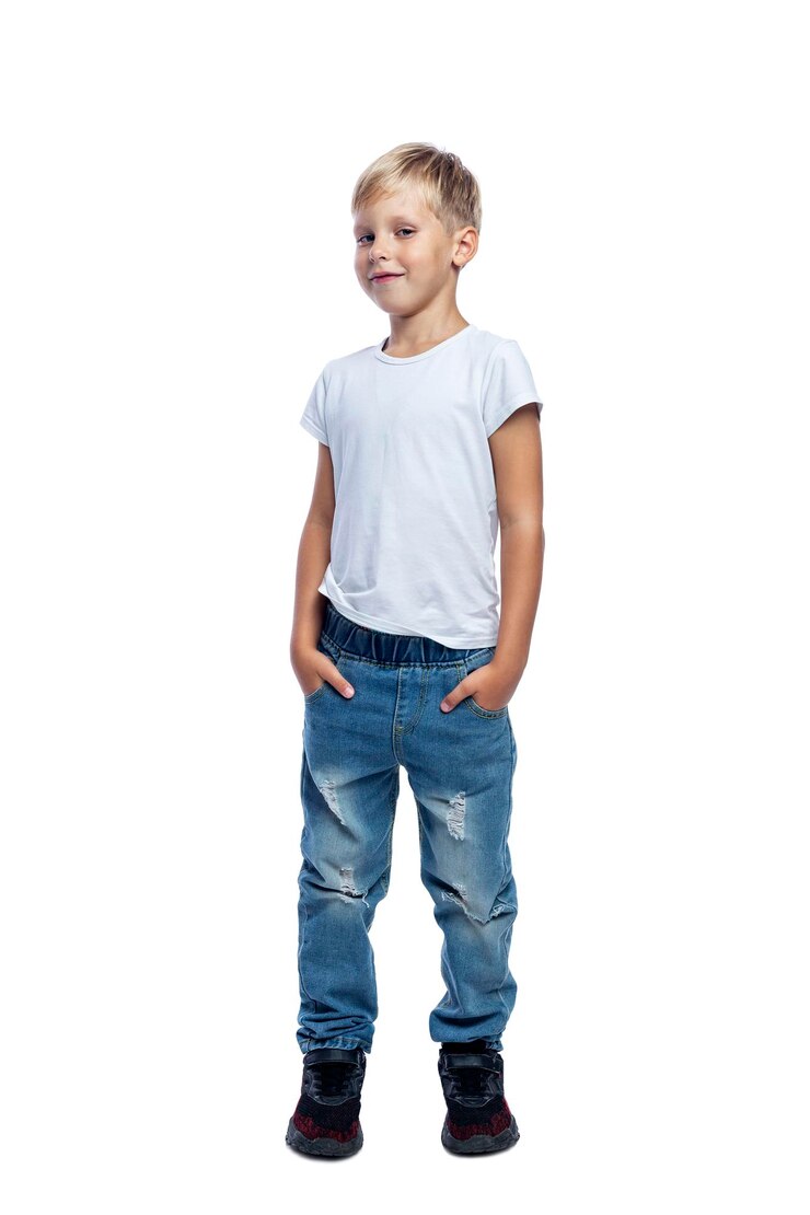 Ragazzo sorridente in piedi con le mani in tasca Un bambino in jeans e una maglietta bianca Positività e fiducia Isolato su sfondo bianco Verticale
