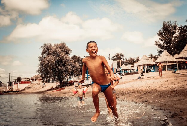 Ragazzo spensierato che corre e si diverte con gli amici sulla spiaggia in estate