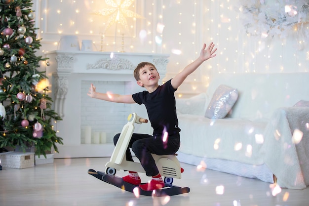 Ragazzo su una barella giocattolo nella stanza di Natale. Bambino felice a Natale a casa