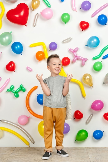 Ragazzo su uno sfondo bianco con palloncini colorati ragazzo che alza le mani su uno sfondo bianco