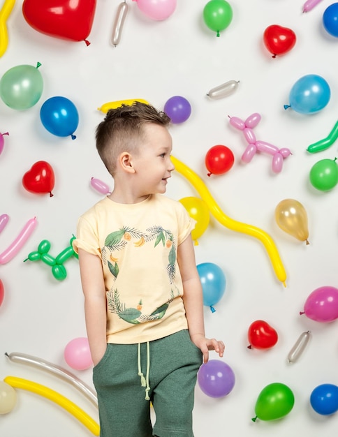 ragazzo su uno sfondo bianco con palloncini colorati. ragazzo in una canotta e pantaloncini su sfondo bianco con palloncini a forma di cuore