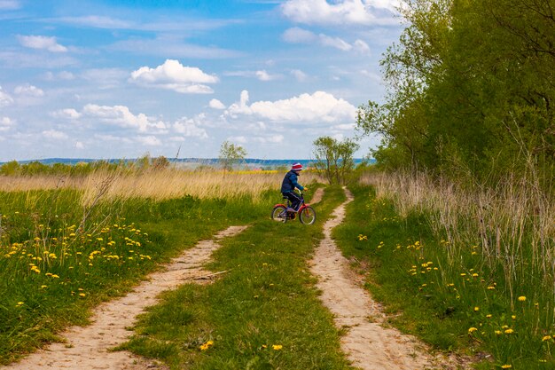 Ragazzo sulla bici sulla strada campestre nel giorno soleggiato