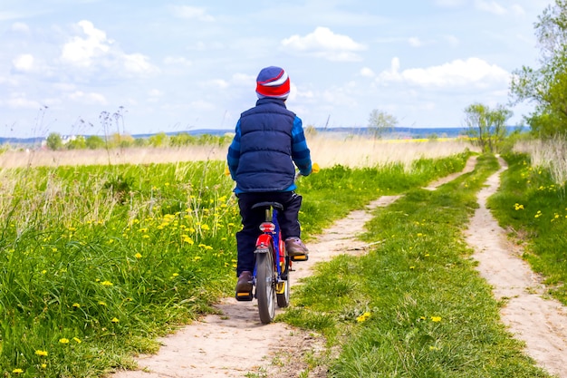 Ragazzo sulla bici sulla strada campestre nel giorno soleggiato