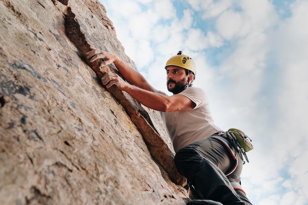 Ragazzo sulla trentina che tiene in mano una roccia mentre si arrampica. Copia spazio