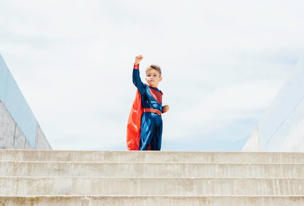 Ragazzo supereroe sullo sfondo delle scale Bambino che si diverte all'aperto Concetto di potere femminile e femminismo