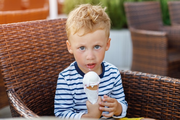 Ragazzo sveglio del bambino che mangia il gelato in caffè