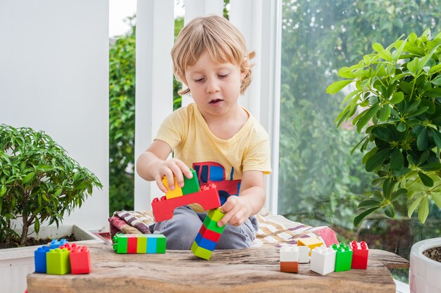 Ragazzo sveglio del bambino con il gioco con un sacco di blocchi colorati di plastica interne