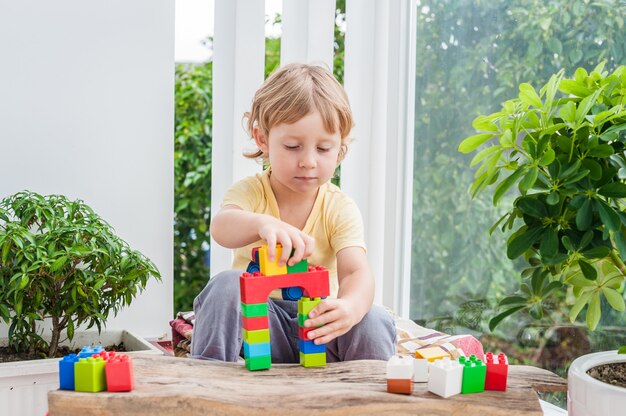 Ragazzo sveglio del bambino con il gioco con un sacco di blocchi colorati di plastica interne