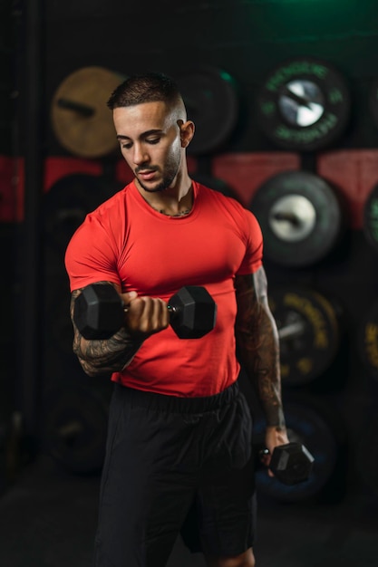 ragazzo tatuato che fa sport in una palestra con maglietta rossa