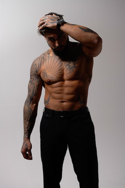 Ragazzo tatuato senza camicia muscolare in studio