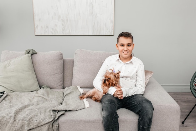Ragazzo teenager sveglio che si siede insieme con un cane sul divano