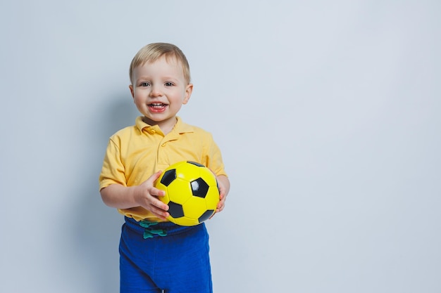 Ragazzo tifoso di calcio di 34 anni in una maglietta gialla con una palla in mano che tiene un pallone da calcio nelle sue mani isolato su uno sfondo bianco Il concetto di ricreazione sportiva in famiglia