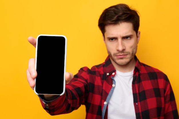 Ragazzo triste che tiene mostrando lo schermo vuoto dello smartphone