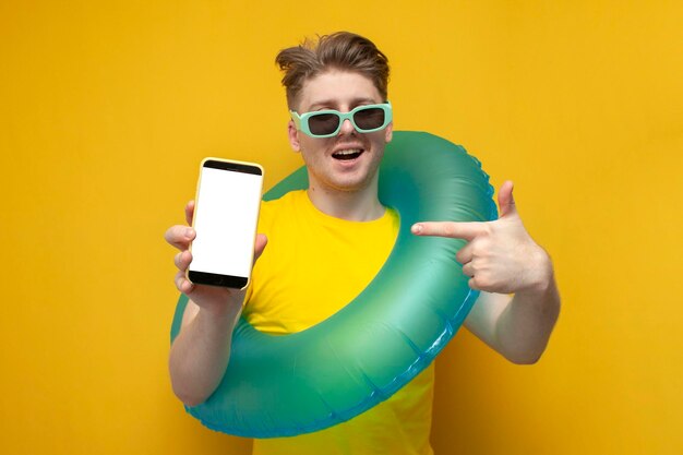Ragazzo turista in estate in vacanza tiene lo smartphone e punta il dito sullo schermo