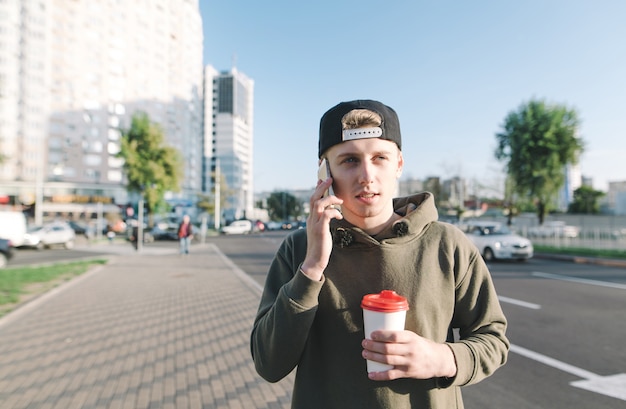 Ragazzo urbano bello con una tazza di carta