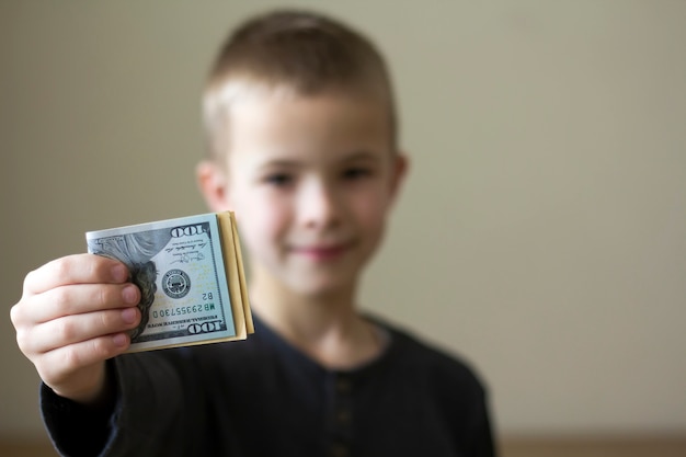 Ragazzo vago allegro che mostra i dollari americani di soldi.