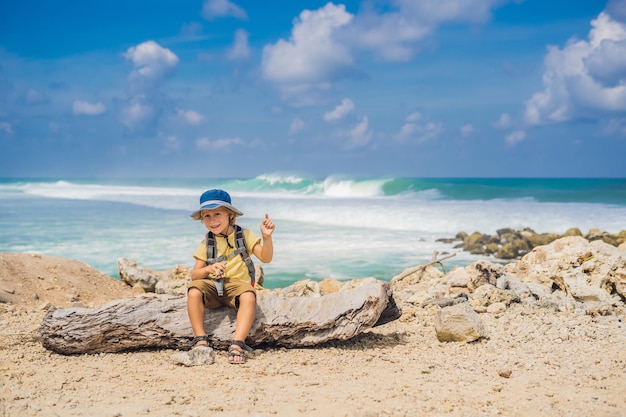 Ragazzo viaggiatore sull'incredibile spiaggia di Melasti con acqua turchese, isola di Bali Indonesia. Viaggiare con il concetto di bambini.