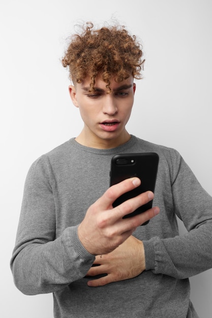 Ragazzo vizioso guardando lo sfondo isolato moda telefono