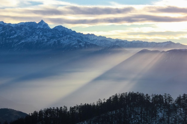Raggi di sole che cadono nella nebbia da dietro la montagna