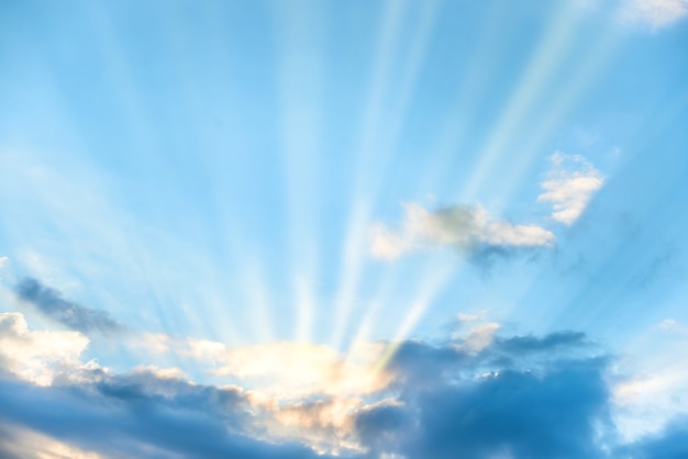 Raggi di sole che splendono attraverso la nuvola sul cielo blu del tramonto