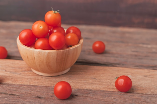 Raggruppi il pomodoro in un posto di legno della ciotola sulla tavola di legno