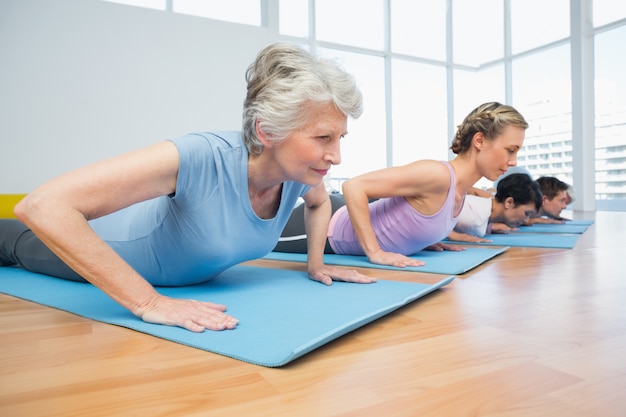 Raggruppi la posa della cobra nella fila alla classe di yoga