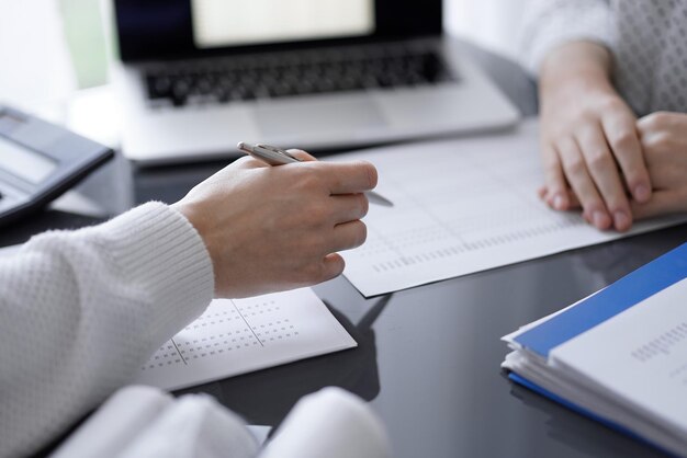 Ragioniere donna che utilizza una calcolatrice e un computer portatile mentre conta le tasse per un cliente. Concetti di controllo aziendale.