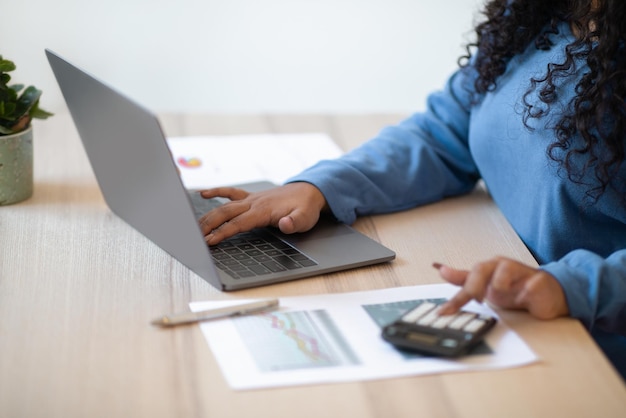 Ragioniere donna irriconoscibile che utilizza computer e calcolatrice