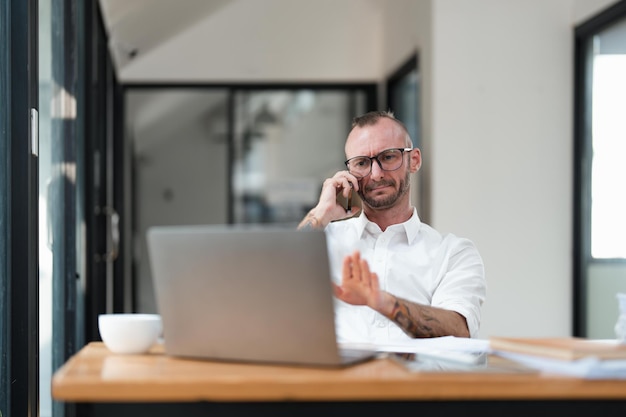 Ragioniere o contabile che utilizza il computer portatile mentre parla di smartphone con la consulenza contabile e per il calcolo del rapporto finanziario fiscale