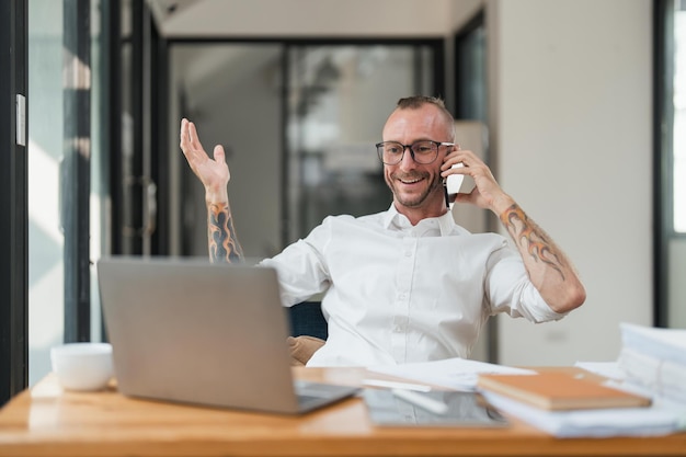 Ragioniere o contabile che utilizza il computer portatile mentre parla di smartphone con la consulenza contabile e per il calcolo del rapporto finanziario fiscale