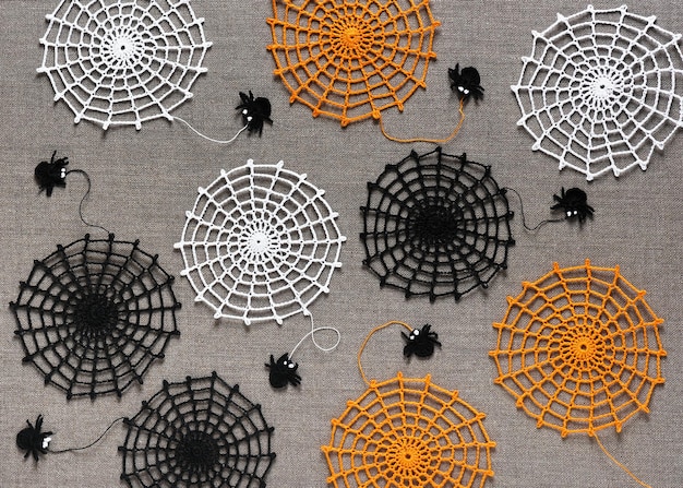 Ragnatele colorate all'uncinetto con ragni divertenti neri su sfondo di tovaglia di lino naturale