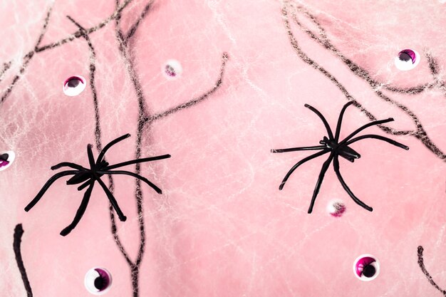 Ragni, ragnatele e occhi di mostro su sfondo pastello rosa di halloween.