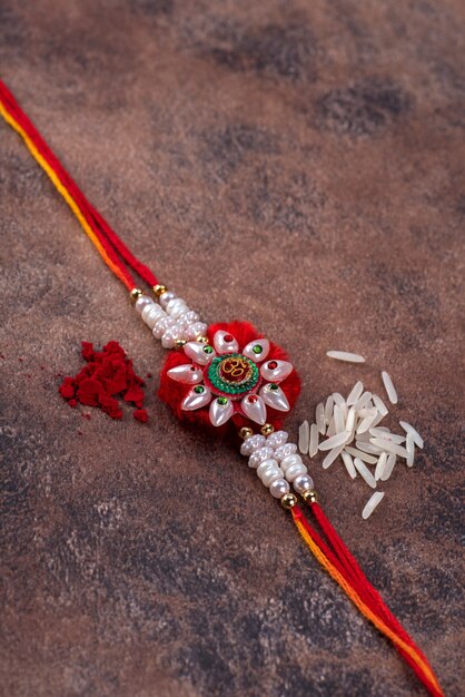 Raksha Bandhan: Rakhi con chicchi di riso e kumkum su sfondo di pietra stone