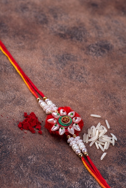 Raksha Bandhan: Rakhi con chicchi di riso e kumkum su sfondo di pietra stone