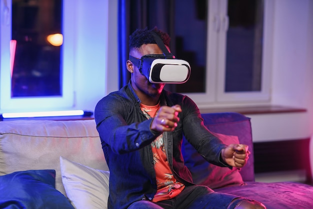 Rallentatore di amichevole allegro americano africano di 30 anni che indossa occhiali per realtà aumentata che si muovono le mani in aria come sullo schermo virtuale