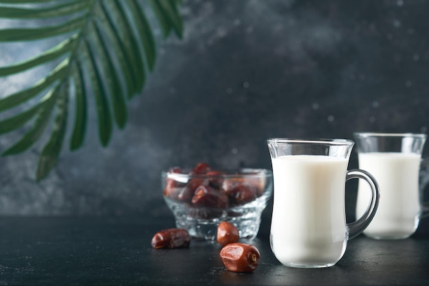Ramadan Kareem cibo e bevande Piatto di datteri bicchiere di latte e ramo di palma da datteri su sfondo nero Giusto stile di vita musulmano Cibo vegetariano Messa a fuoco selettiva