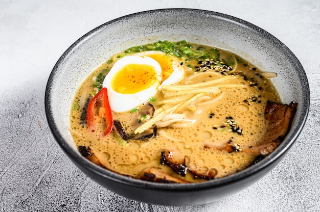 Ramen di zuppa giapponese tradizionale con brodo di carne, spaghetti asiatici, alghe, carne di maiale affettata, uova. Sfondo bianco. Vista dall'alto