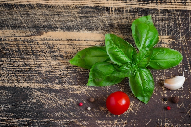 Rametto di basilico, pomodorini, spezie sul vecchio tavolo di legno