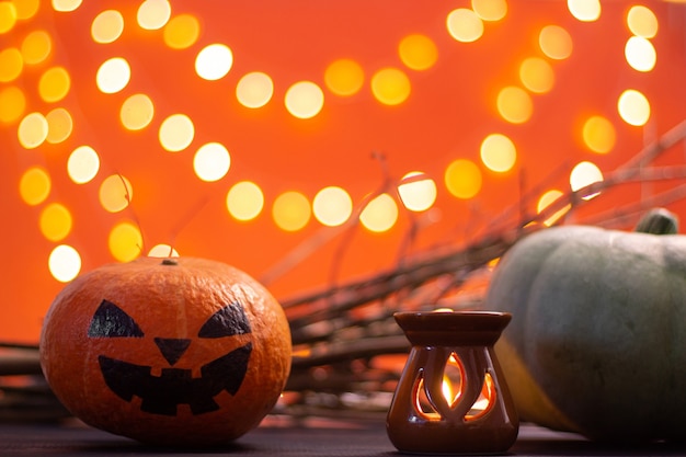 Rami, candele e zucche su uno sfondo arancione con bokeh. Halloween. Copia spazio.