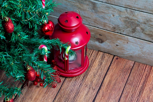 Rami di abete, decorazioni natalizie e lanterna rossa. fondo in legno