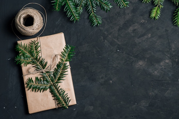 Rami di abete e scatola regalo di Natale su sfondo nero. Semplice confezione regalo