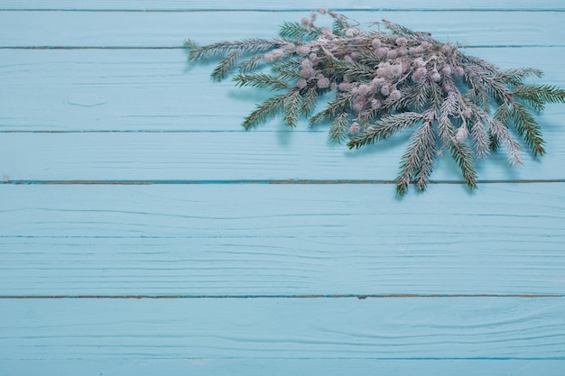 Rami di abete nella neve sulla superficie di legno blu