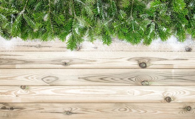 Rami di albero di Natale con decorazioni di neve su fondo in legno