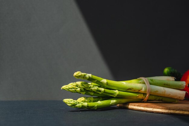 Rami di asparagi verdi freschi su una tavola di legno sfondo grigio scuro vista dall'alto Concetto di tendenza di base con spazio per la copia