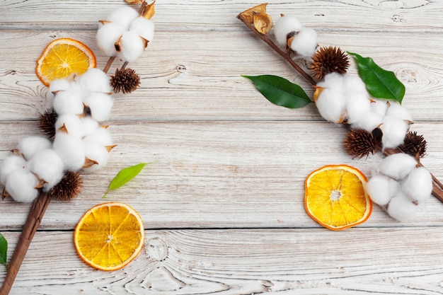 Ramifichi con i fiori del cotone su fondo di legno