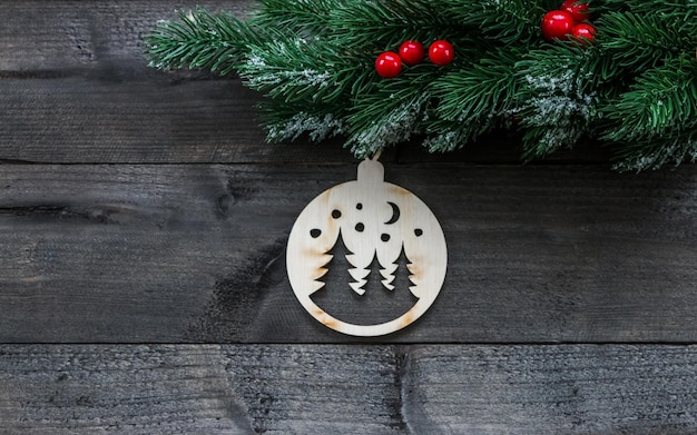 Ramo di albero di Natale decorato con coni di neve e un giocattolo su un tavolo di legno scuro