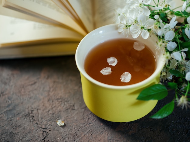 Ramo di ciliegio in fiore di primavera, una tazza di tè e un libro